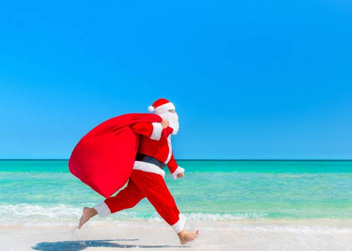 Santa with presents running on Pensacola Beach